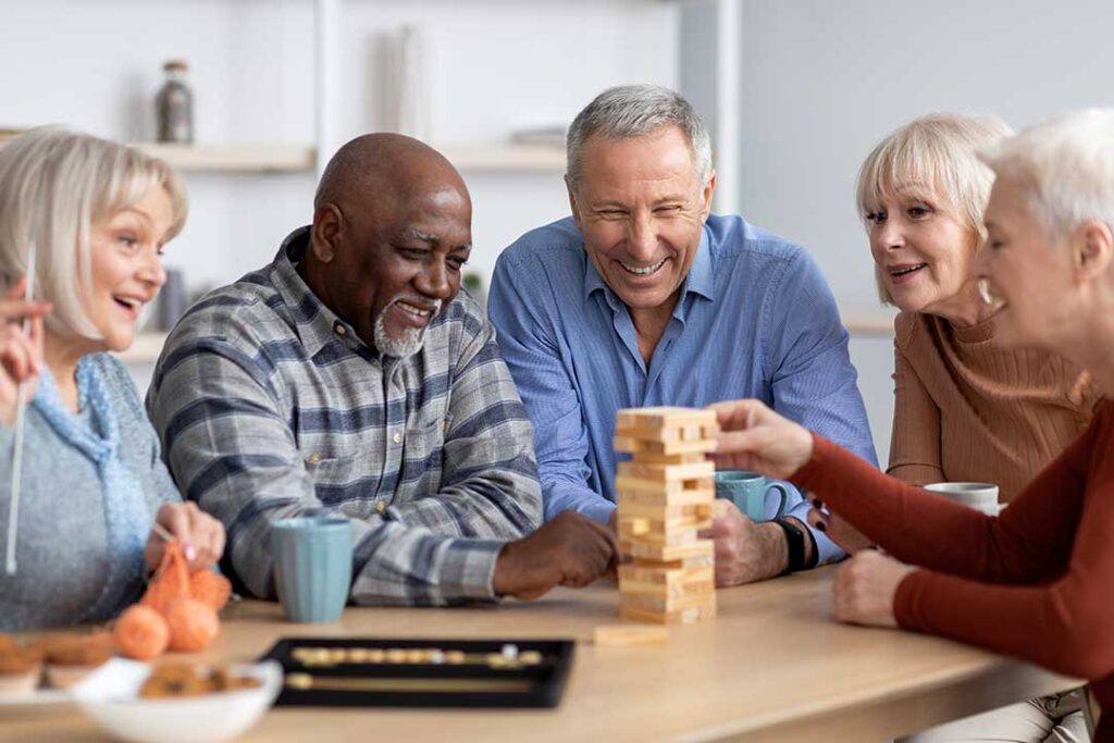 Seniors gathered around a dining table enjoying a shared meal in a bright, comfortable dining room.
