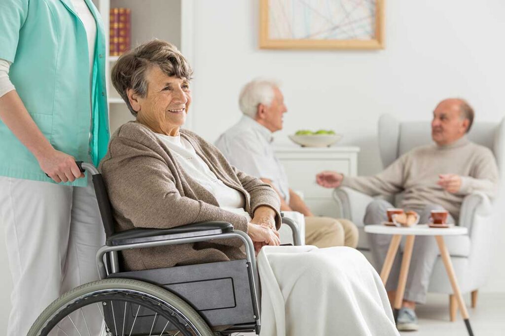 Caregiver and older resident reviewing a personalized care plan at a table in a bright assisted living room.